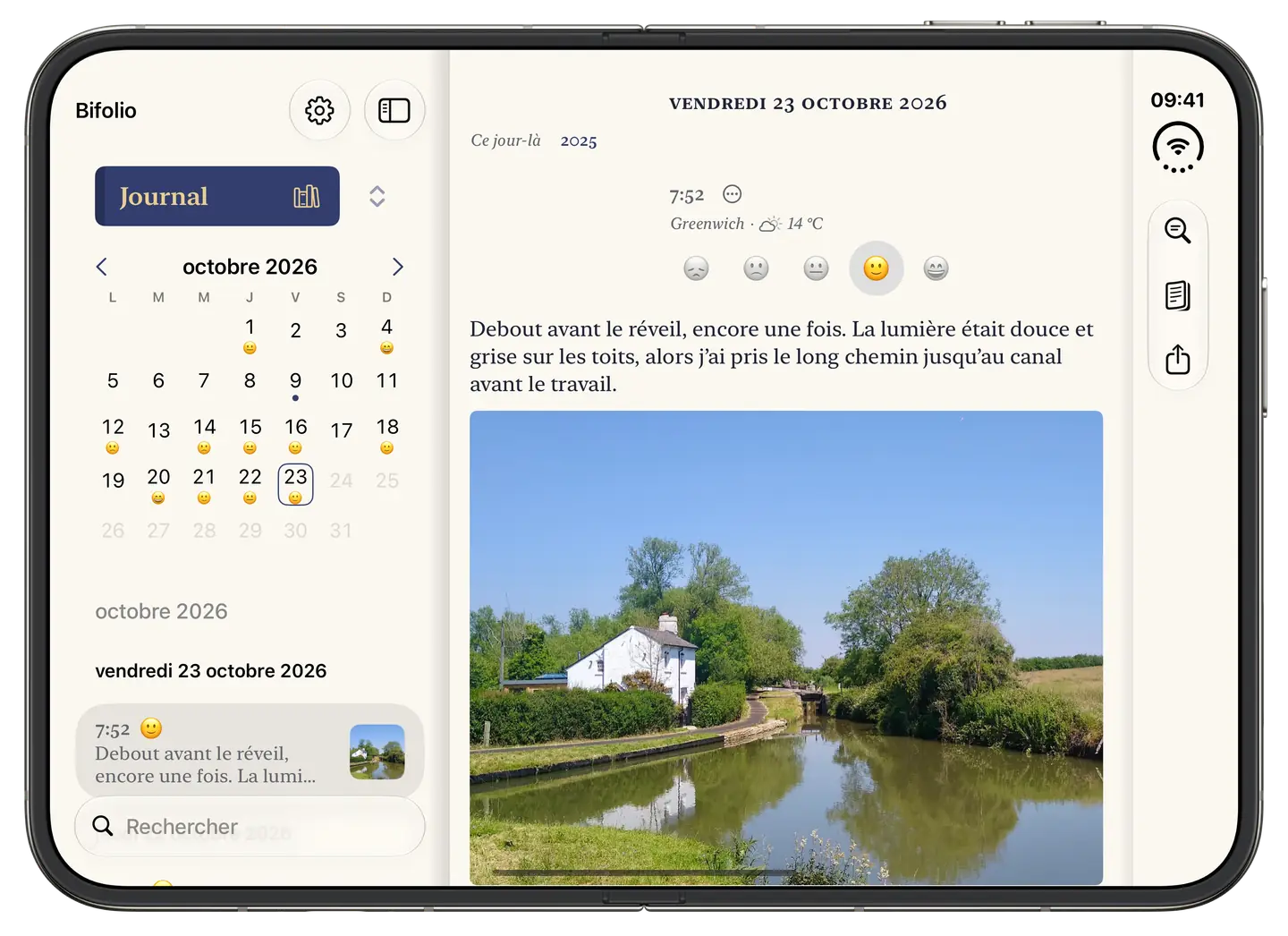 Bifolio ouvert sur iPhone Duo : le calendrier d’octobre et les entrées du jour à gauche, et à droite l’entrée du vendredi 23 octobre, avec la photo d’une maison au bord d’un canal.
