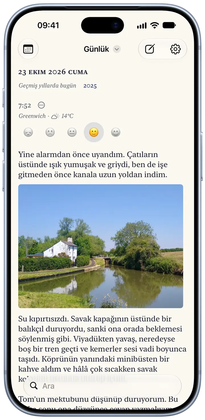 Bir iPhone ekranında Bifolio’da bugünün sayfası, 23 Ekim 2026 Cuma: Greenwich’te saat 7:52’de yazılmış bir kayıt, 14°C ve parçalı bulutlu hava, ruh hali için seçilmiş bir gülümseme, sabah erkenden yapılan bir yürüyüşü anlatan kısa bir paragraf ve bir kanal savağının yanındaki beyaz bir evin fotoğrafı.