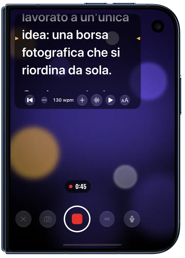 Eyeline in registrazione sullo schermo esterno di un iPhone Duo chiuso: il copione subito sotto la fotocamera frontale, la riga da leggere segnata in ambra, a 130 parole al minuto, con la ripresa a 0:45.